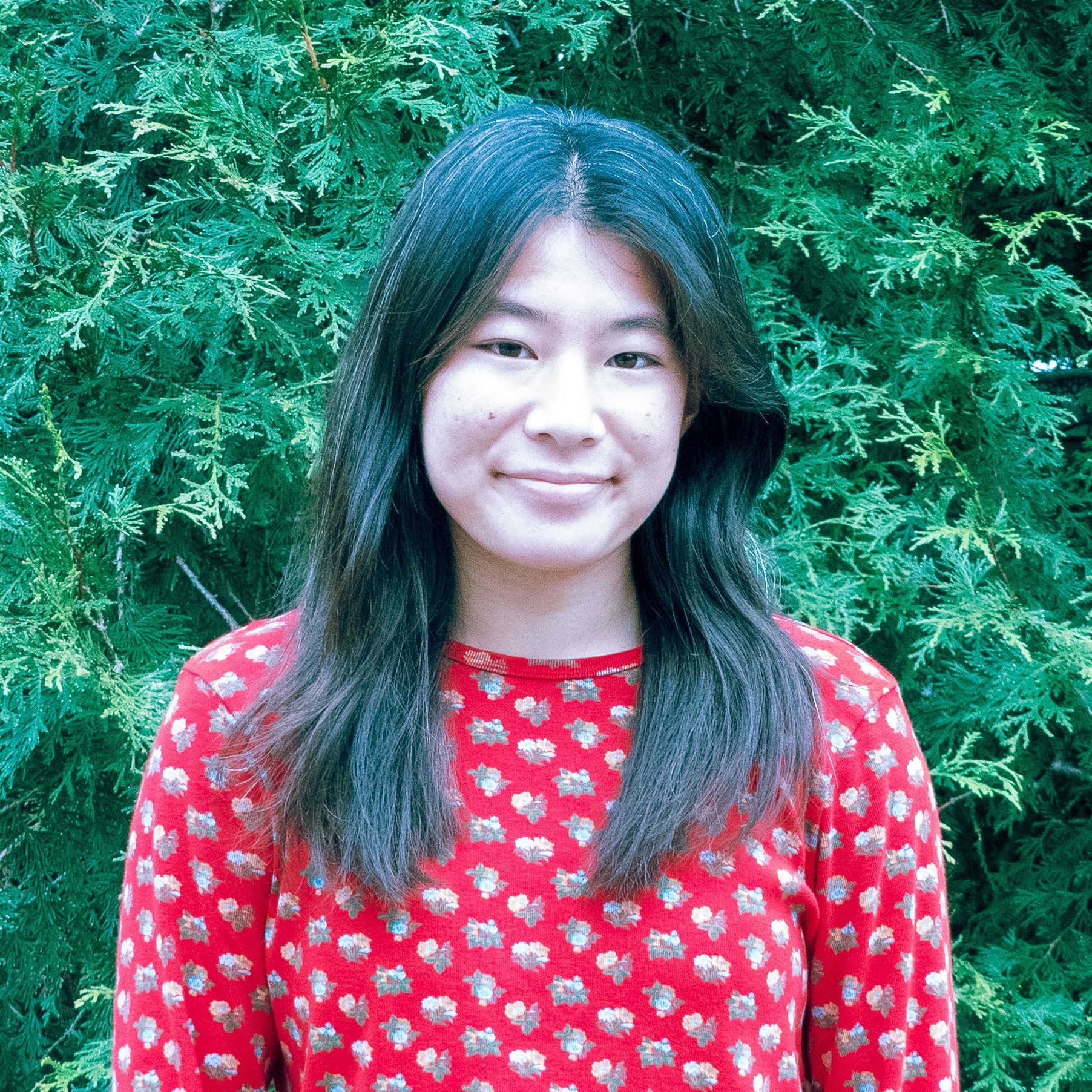 Young asian woman with dark brown hair and red shirt smiles at the camera