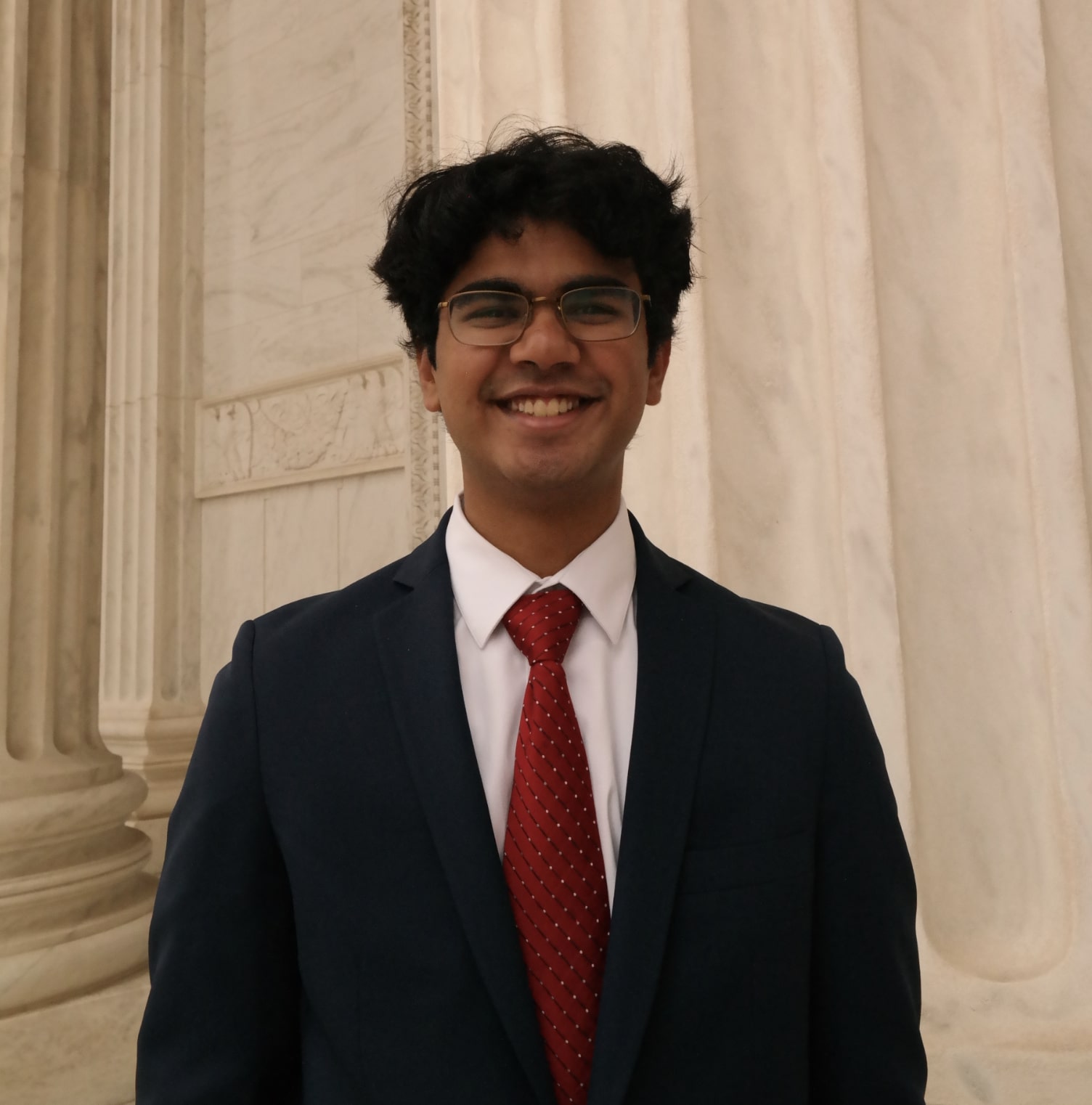 Ani, a young Indian man wearing a blue suit, smiles at the camera.