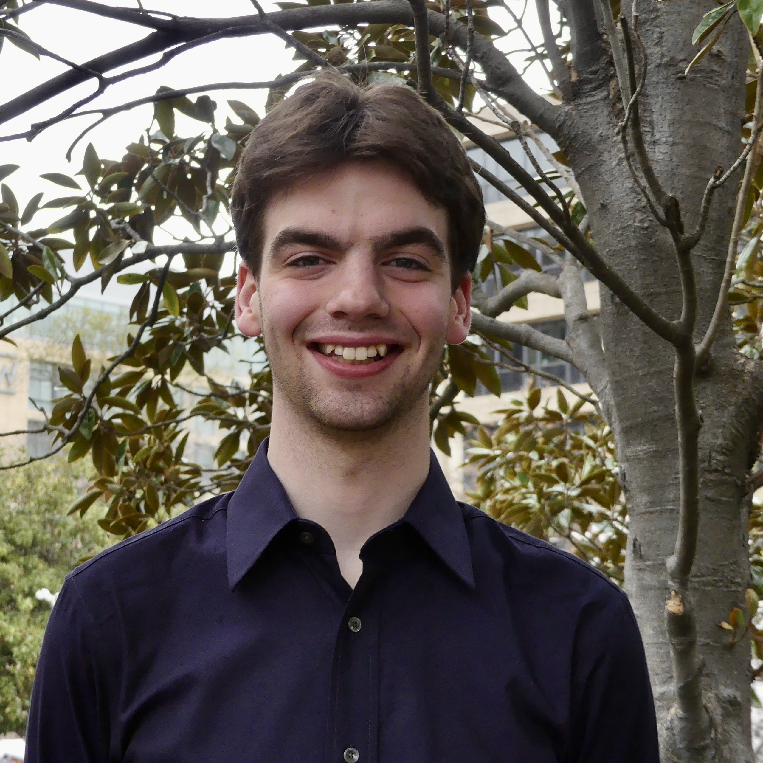 Nick, a young man with wavy brown hair and green eyes, smiling.