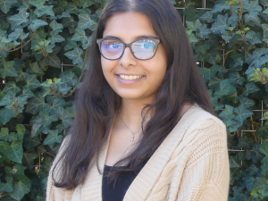Ankita, a young woman with straight dark hair and glasses, smiles at the camera.