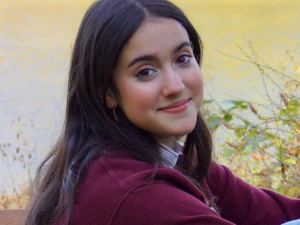 Alex, a young white woman with dark hair and brown eyes, smiling.