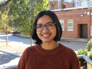 Ruju, an Indian woman with short hair wearing a brown sweater