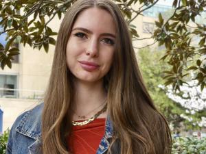 Rafa, a brunette woman with long hair and a red shirt smiles at the camera
