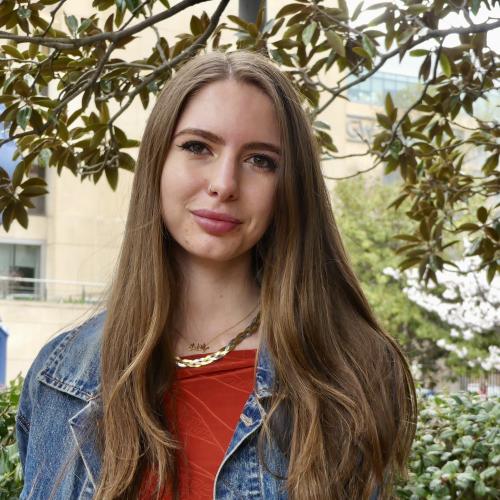Rafa, a brunette woman with long hair and a red shirt smiles at the camera