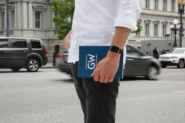 A man standing on the street holding a GW folder