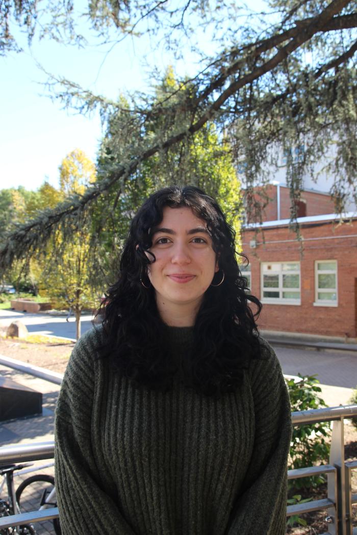 Mariam, young white woman with curly brown hair, smiling at the camera