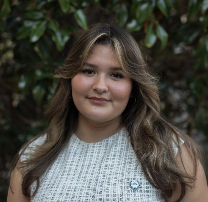 Claire, a young Latina with straight brown hair, smiles at the camera.
