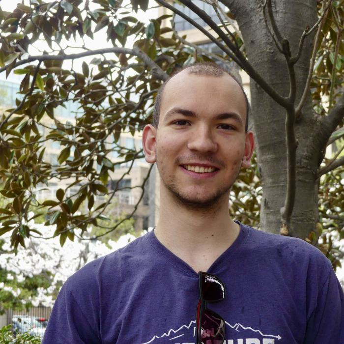 Felix, a brown-haired young European man, is pictured outdoors looking into the camera.