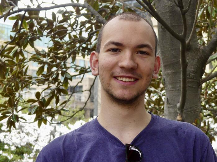 Felix, a brown-haired young European man, is pictured outdoors looking into the camera.